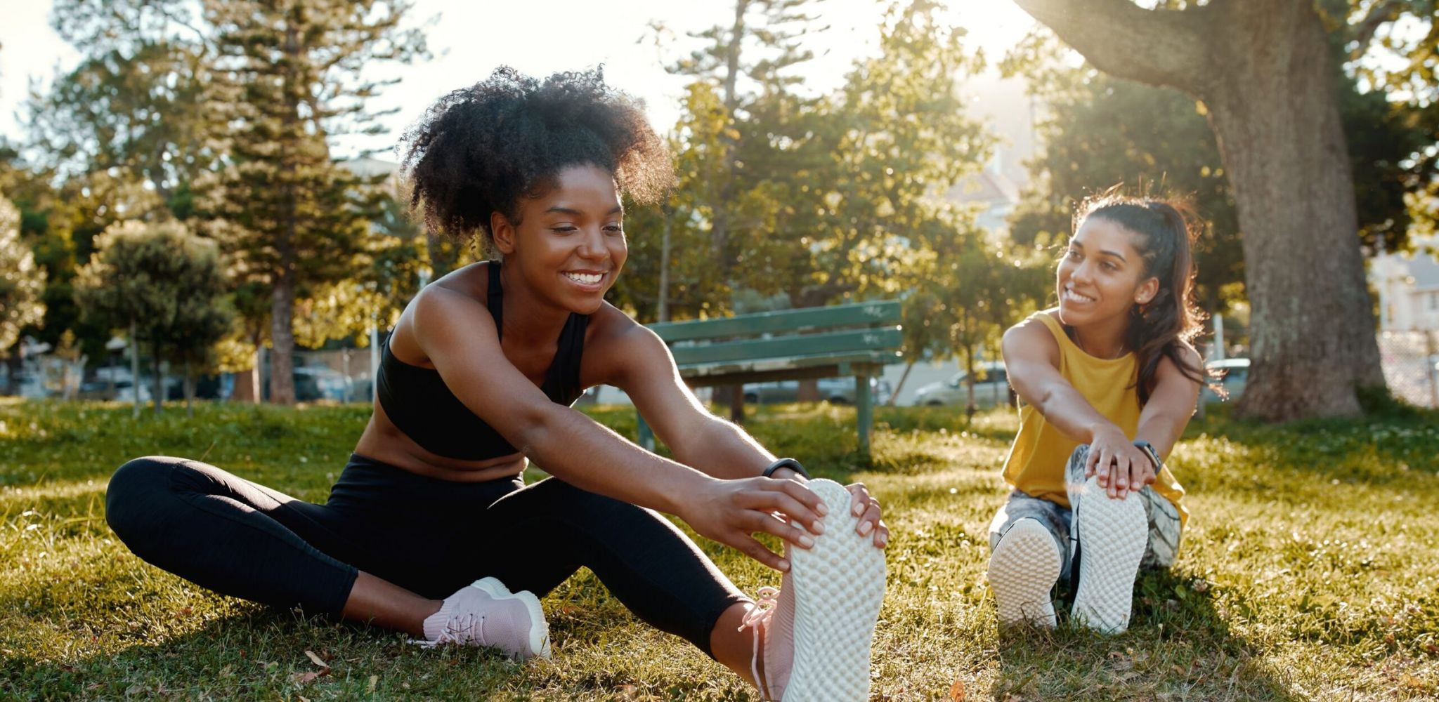 The Townes at Hatcher Creek female diverse friends doing stretching exercise in the park - diverse friends warming up before doing group exercise